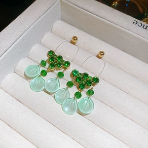 Detail shot of forest style drop earrings with green stones and leaf pendants in a jewelry box