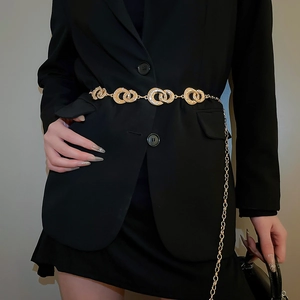 Detail of interlocking gold rings with rhinestones on a slim waist chain belt