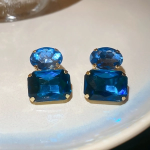 Close-up of vintage style oval and square blue crystal stud earrings in gold claws