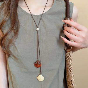 Detail of ethnic shell pendant necklace with wood beads on olive green linen garment
