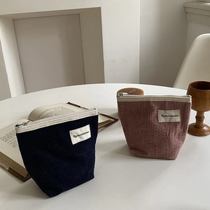 Detailed texture of corduroy cosmetic bags in navy blue and dusty rose with zipper closures