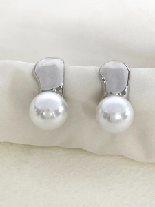 Détail macro de boucles d'oreilles irrégulières en métal argenté avec perles sur soie