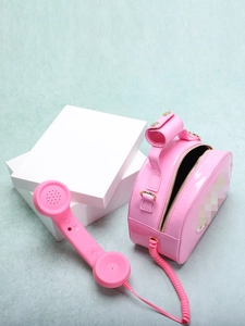 Detail of creative pink telephone-shaped crossbody bag featuring glossy patent leather finish