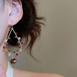 Detailed view of handmade beaded drop earrings with red and brown faceted crystals