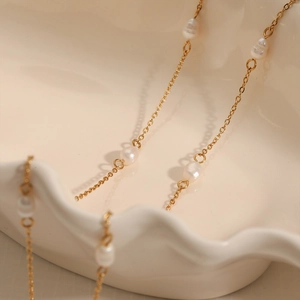 Elegant gold-plated stainless steel necklace with baroque pearls on a white tray