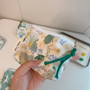 Detail view of the mini floral cotton pouch showing simple wish label and green rope zipper pull