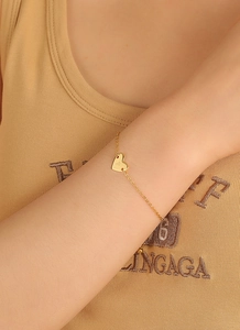 Détail d'un bracelet doré avec un pendentif en forme de cœur et une lettre P gravée