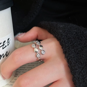Detailed macro of a silver open ring with zircons worn in a lifestyle coffee setting
