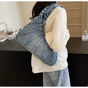 Sac bandoulière en denim bleu foncé avec détails vintage porté par un mannequin