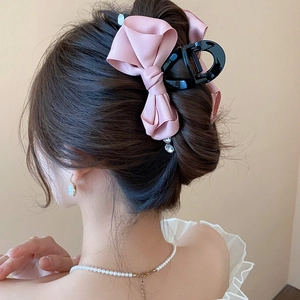 Detail of pink satin bow hair claw clip with rhinestone pendant worn by a model