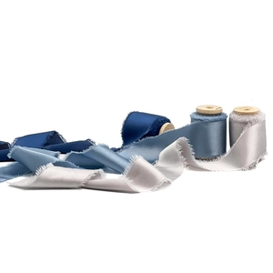 Frayed edge satin chiffon ribbons in shades of blue and silver on wooden spools