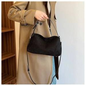 Close-up of black suede tote bag with silver hardware on a khaki coat outfit