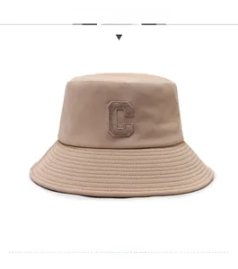 Détail du chapeau bob en toile beige avec écusson C marron et coutures sur le bord