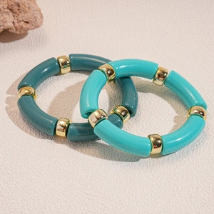Dettaglio dei bracciali tubolari in acrilico color ciano scuro e chiaro con oro