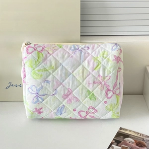 Detailed close-up of quilted floral cosmetic bag with butterfly patterns and brand label