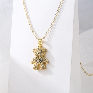 Gold plated teddy bear necklace with micro-paved cubic zirconia on white stand