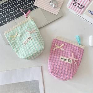 Detail of checkered cosmetic bags with satin bows and seersucker texture in soft pastels