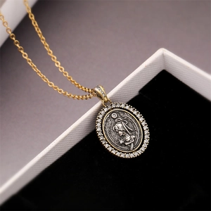 Detailed shot of retro oval coin pendant with rhinestone edges in black velvet box