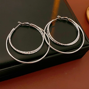 Detalle de pendientes de triple aro plateado con textura de corte diamante sobre caja