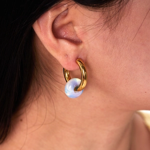 Close-up of 18K gold plated hoop earring with a light blue translucent gemstone on model