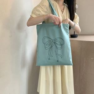Detailansicht der hellblauen Canvas-Tragetasche mit schwarzem Schleifendruck am Model