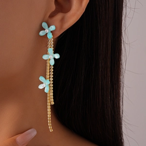 Close-up of light blue flower tassel earrings with pearls and rhinestones on a model