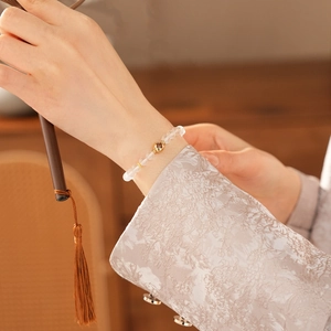 Detail of white crystal beaded bracelet with gold flower bead on a female wrist