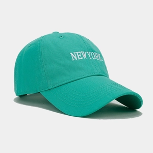 Close-up of white NEW YORK embroidery on a green cotton baseball cap with neat stitching