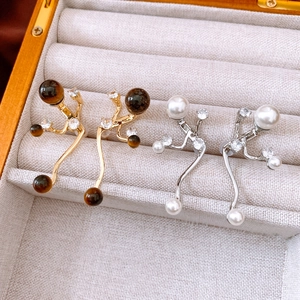 Detail of branch design earrings with tiger eye stone and white pearls in a jewelry box