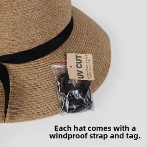 Detail of woven straw sun hat with black ribbon, detachable wind rope, and UV protection tag
