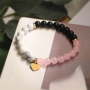 Detail of beaded bracelet featuring pink crystal, marble beads and gold heart charm