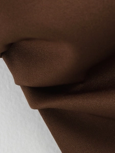 Detailed macro shot of dark brown twill fabric texture with elegant pleats
