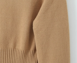 Dettaglio della trama in maglia color cammello e bordo a coste del maglione autunnale