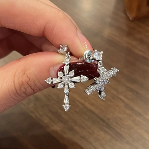 Elegant silver starburst earrings with sparkling crystals held in a hand-close up view