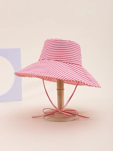 Detail of red and white striped wide brim sun hat with a decorative bow on a wooden stand