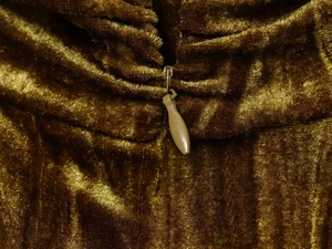 Dettaglio di un abito in velluto senape dorato con cerniera abbinata e trama del tessuto