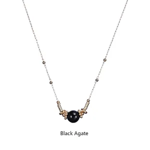 Detail of delicate gold necklace featuring black agate bead and polished gold ring accents