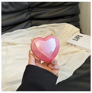 Detail of pink heart-shaped bag with geometric facets and elegant gold chain strap