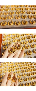 Macro detail of large gold hoop earrings featuring a unique hammered metal texture surface
