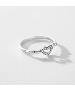 Macro shot of silver hollow heart-shaped ring with small diamonds on white textured paper