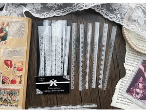 Detailed view of white lace PET stickers in floral designs on a vintage wooden desk