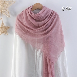 Détail d'une écharpe en coton et lin rose avec bords effilochés sur cintre blanc