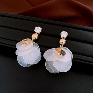 Macro view of gold bamboo earrings with clear crystal stud and white shell disks