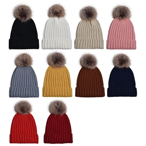 Ten colorful knit beanies with fluffy faux fur pom-poms shown in multiple vibrant hues