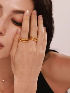 Detail of 18k gold plated double-layer twisted rings on model's hand with metallic luster