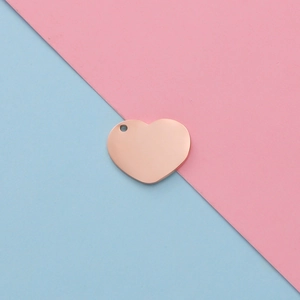 Polished rose gold heart-shaped stainless steel pendant on a blue and pink background