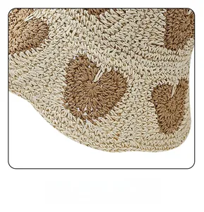 Detail of soft foldable straw sun hat showing flexible brim and heart pattern texture