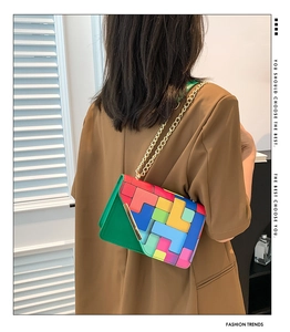 Detail of colorful geometric patchwork square bag with gold chain strap on shoulder