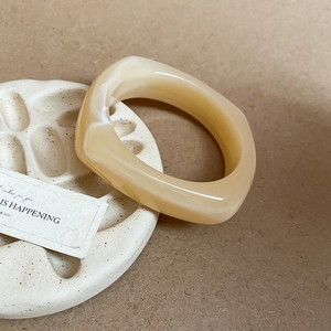 Detail of cream acrylic resin bangle featuring a thick marbled geometric design on base