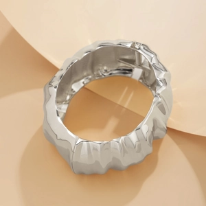 Detailed macro view of irregular crumpled silver alloy bracelet with hinge closure